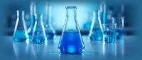Blue chemical solution in glass flask surrounded by laboratory equipment for scientific research and experimentation in modern lab setting.