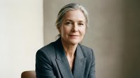 Professional mature Caucasian businesswoman with gray hair in elegant suit smiling confidently in modern office setting for corporate leadership concepts.