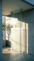 Modern building entrance with frosted glass door engraved with Welcome text, concrete walls, sunlight shadows, and a potted tree in minimalist lobby.
