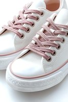 White sneakers with pink laces and trim on clean white background, close-up view showing detailed texture of braided shoelaces and rubber sole.