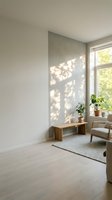Minimalist interior space with natural sunlight casting geometric shadows on neutral walls, wooden bench, potted plants, and comfortable seating for home design and lifestyle projects.