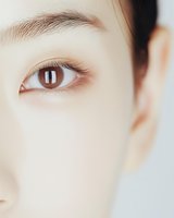 Close-up of Asian female brown eye with natural makeup, showing delicate eyelashes and eyebrow against light skin tone, suitable for beauty and cosmetic advertising.
