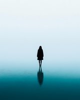 Silhouette of lone woman standing on reflective water surface against misty turquoise background, creating surreal minimalist scene with mirror effect.