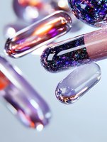 Trendy nail art design featuring metallic chrome and galaxy-inspired glitter polish in purple and rose gold tones, macro shot showing glossy finish and light reflections.