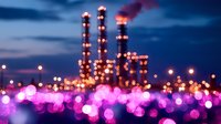 Industrial refinery silhouette against dramatic night sky with vibrant pink and purple bokeh lights creating dreamy atmospheric foreground, energy sector concept.