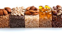 Healthy superfood ingredients arranged in rows showing nuts, seeds, grains and supplements on white background, panoramic composition for food industry.