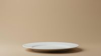Empty white plate on beige background, isolated tableware for product display, food photography, and design mockups.