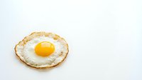Fried egg with golden yolk and crispy edges isolated on white background for breakfast menu design and culinary projects.
