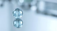 Two transparent blue glass spheres stacked vertically with reflection on white surface, suitable for abstract design, backgrounds, and modern artistic projects.