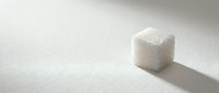 Sugar cube on white surface with shadow, isolated ingredient for baking, cooking, and beverage sweetening applications.