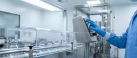 Pharmaceutical technician in protective gear operating tablet manufacturing equipment in sterile cleanroom facility for drug production and quality control.