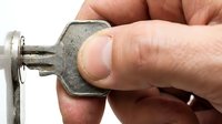 Hand holding an old metal key against white background, closeup of fingers gripping vintage key for lock opening, security and access concept.