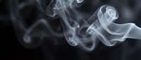 Soft white smoke swirls gracefully against a dark black background, creating an ethereal, mysterious atmosphere with flowing abstract curves.
