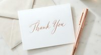 Elegant thank you card with rose gold calligraphy on white paper, accompanied by matching pen and cream envelope for wedding stationery.