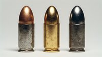 Three metallic bullets in copper, gold, and silver tones arranged in a row against neutral background, showcasing ammunition variety for firearms enthusiasts.