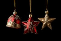 Red and gold vintage Christmas ornaments hanging on golden ribbons against dark background, featuring bell, snowflake star and classic star decorations.