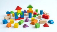 Colorful wooden building blocks set with geometric shapes including cubes, cylinders, triangles and rectangles scattered on white background for educational play.