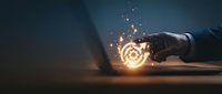 Hand holding glowing target symbol with light sparks, representing goal achievement, business strategy, focus and success concept for marketing and corporate projects.