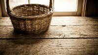 Empty wicker basket on rustic wooden table near window with natural light for home decor and storage solutions.