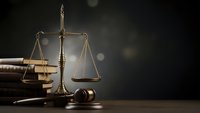 Scales of justice with gavel and law books on wooden desk against dark background for legal services, attorney office, courthouse concepts.