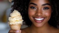 Young African American woman enjoying vanilla ice cream cone with bright smile and natural curly hair in warm indoor setting for summer treats and desserts.