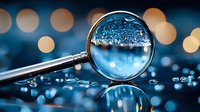 Magnifying glass revealing water droplets and bubbles with blurred bokeh lights in background, symbolizing inspection, analysis, and discovery for research, science, and investigation concepts.