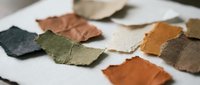 Colorful leather samples scattered on white surface showcasing various textures and natural tones for crafting and design projects.
