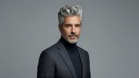 Mature man with gray hair and beard wearing dark blazer and turtleneck against neutral background. Professional portrait suitable for business, corporate, and lifestyle design projects.