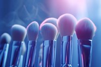 Professional makeup brushes with soft pink bristles in blue and purple lighting, creating dreamy atmosphere for cosmetics and beauty industry marketing.