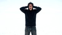 Young man in black hoodie covering ears with hands showing stress or overwhelm on white background isolated for design use.