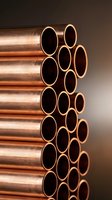 Stack of shiny copper pipes arranged in rows showing circular openings, industrial plumbing materials for construction and manufacturing projects.
