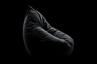 Black bean bag chair with dramatic lighting and deep shadows against dark background, modern minimalist furniture design for contemporary interior spaces.