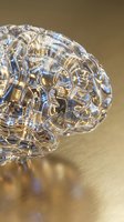 Transparent glass brain with golden circuit patterns and glowing neural pathways on reflective surface representing artificial intelligence and technology.