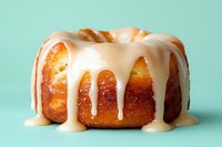 Freshly baked bundt cake with creamy vanilla glaze dripping down sides, presented on mint green background for food photography.