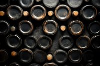 Dark wine bottles arranged in traditional wine rack showing bottom ends, creating geometric pattern with cork stoppers visible. Rustic cellar storage concept.
