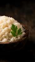 Cooked white rice in wooden bowl garnished with fresh parsley on dark rustic background for culinary and food photography projects.