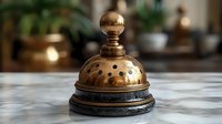 Vintage brass service bell on marble counter with blurred warm background. Antique hotel concierge bell with patina and decorative perforated dome design for hospitality concept.