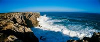 Dramatic coastal cliffs with crashing ocean waves and clear blue sky, perfect for travel and nature backgrounds.