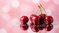 Fresh red cherries with water droplets on reflective surface against soft pink bokeh background for summer fruit photography and healthy eating concepts.