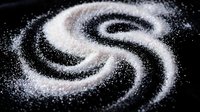 Swirling white granulated sugar arranged in spiral pattern on dark background, suitable for food photography, culinary design, and sweetener product marketing.