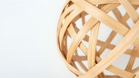 Woven bamboo strips forming spherical basket pattern on white background, natural eco-friendly material with geometric lattice design creates modern minimalist look.