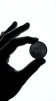 Hand holding eco-friendly coin with leaf symbol and save text in black and white silhouette style for environmental awareness campaigns.