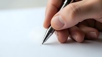 Hand holding black pen ready to write on clean white paper surface for business documentation and creative writing projects.