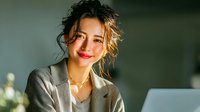 Young professional woman with blonde hair smiling while working on laptop in modern office environment. Business success and workplace productivity concept.