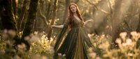 Young woman in medieval fantasy dress dancing in enchanted forest with golden sunlight filtering through trees creating magical atmosphere for storytelling projects.