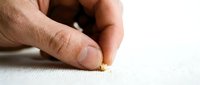 Close-up of a hand placing a small gold object on a white textured surface, suitable for business, decision-making, and investment concepts.