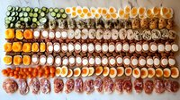 Colorful rows of assorted sushi rolls and nigiri arranged in neat lines on light background, showcasing variety of fresh ingredients and traditional Japanese cuisine.