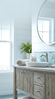 Modern coastal bathroom vanity with vessel sink, round mirror and weathered wood cabinet in bright natural light for home renovation projects.