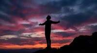 Person silhouette with open arms against dramatic sunset sky with pink and purple clouds, freedom and achievement concept for motivational content.