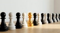 Golden pawn stands out among black and white chess pieces in row, symbolizing leadership, uniqueness, and strategic thinking in business concepts.